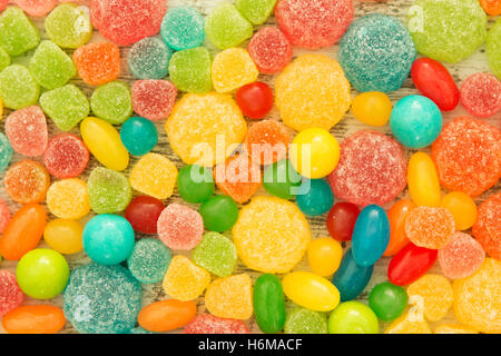 Colorful jelly beans of different sizes close to wallpaper Stock Photo