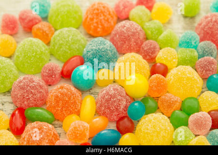 Colorful jelly beans of different sizes close to wallpaper Stock Photo