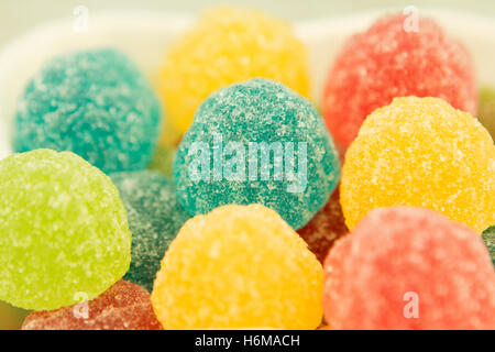 Colorful jelly beans of different sizes close to wallpaper Stock Photo