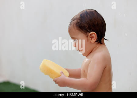 Funny kid showering in the yard for a summer afternoon Stock Photo