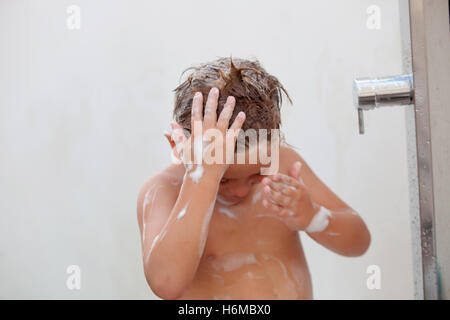 Funny kid showering in the yard for a summer afternoon Stock Photo