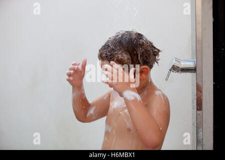 Funny kid showering in the yard for a summer afternoon Stock Photo