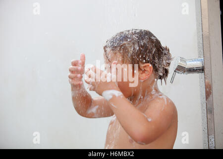 Funny kid showering in the yard for a summer afternoon Stock Photo