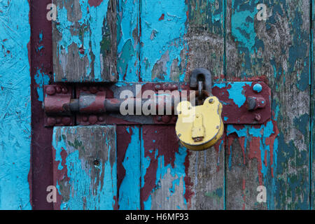 padlocked old door with colorful flaking paint Stock Photo
