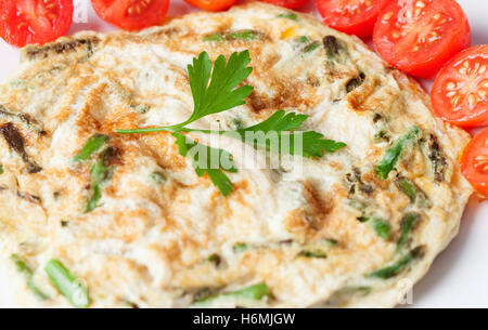 Juicy asparagus omelette surrounded by small tomatoes Stock Photo