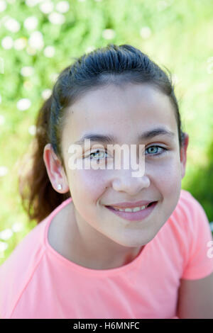 Happy casual preteen girl looking at camera outside Stock Photo