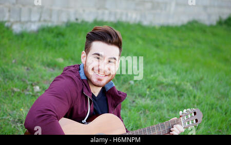 Cool handsome guy with beard playing guitar at outside Stock Photo