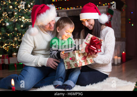 holidays, presents, christmas concept - happy family - mother, father and kid boy open gift box