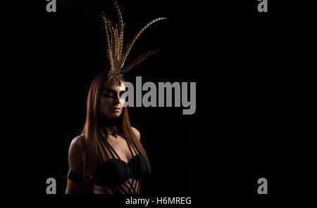 Tanned female model in amazonian superhero style outfit with feather headdress Stock Photo