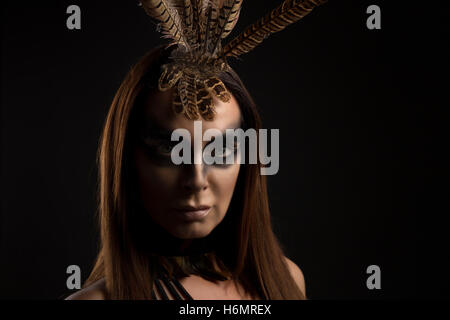 Tanned female model in amazonian superhero style outfit with feather headdress Stock Photo