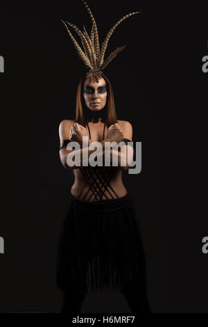 Tanned female model in amazonian superhero style outfit with feather headdress Stock Photo