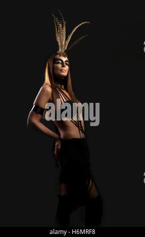 Tanned female model in amazonian superhero style outfit with feather headdress Stock Photo