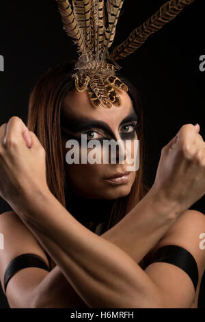 Tanned female model in amazonian superhero style outfit with feather headdress Stock Photo