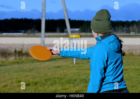 Young woman on disc golf course aiming disc to target. Stock Photo