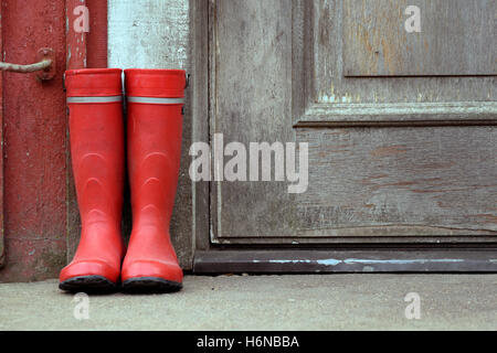 Red wellies outside of old house. Stock Photo