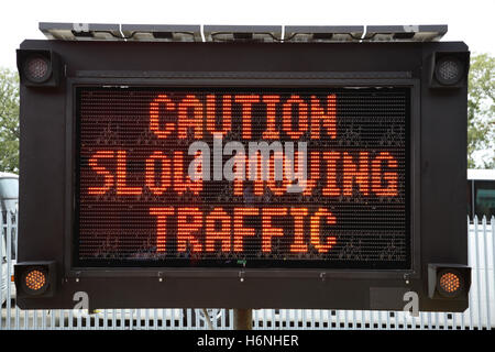 Closeup of a roadside mobile, solar powered dot-matrix road sign showing the message: Caution Slow Moving Traffic Stock Photo