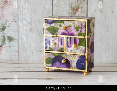 A handmade mini chest of drawers decoupaged in vintage papers and gilded with gold leaf Stock Photo