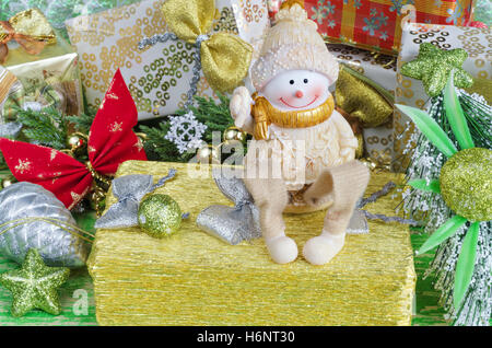 Christmas composition with decorations. Cheerful Snowman sitting on a gift. Stock Photo