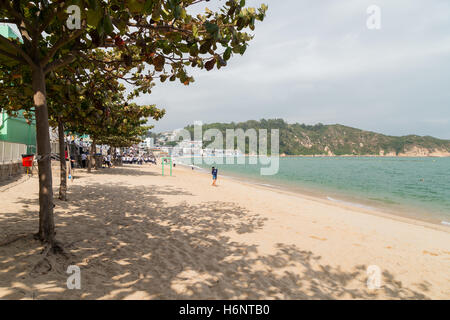 Trees and schoolchildren at the Tung Wan Beach on the Cheung Chau Island in Hong Kong, China. Stock Photo