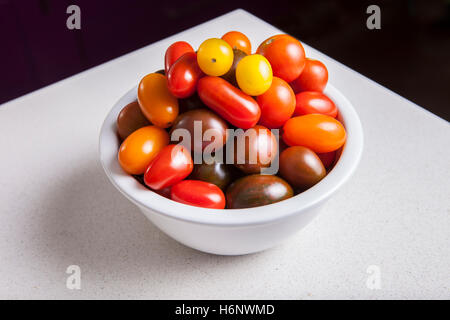 Clay bowl full of several varieties of cherry tomatoes. Studio take Stock Photo