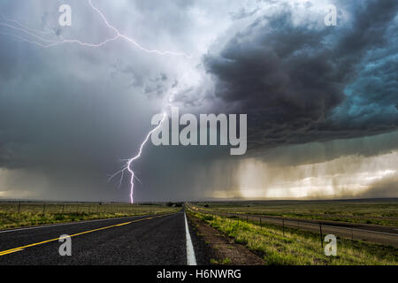 Bright lightning striking over a long road during a storm near Springer, New Mexico Stock Photo