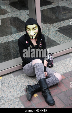 A female activist wearing a Guy Fawkes mask and a hoodie at a protest against the wall street and bank bailouts in Sacramento, Stock Photo
