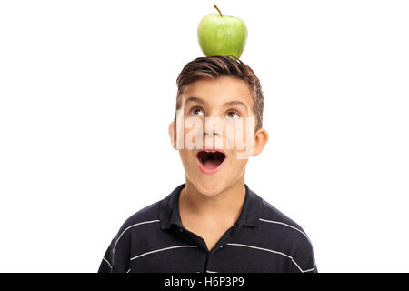 Overjoyed little boy looking at an apple on his head isolated on white background Stock Photo