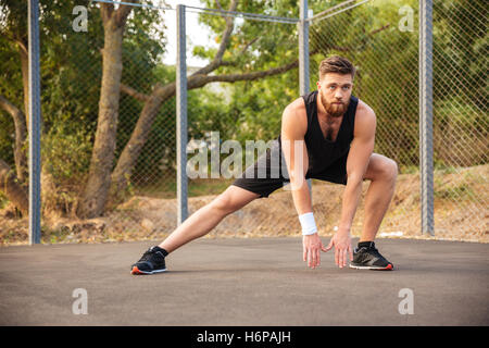 Attractive young male athlete stretching his legs outdoors Stock Photo