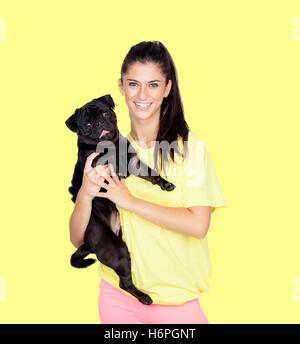 Brunette girl with her pug dog on yellow background Stock Photo