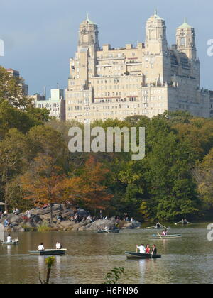 Row boats with couples in Central Park, NY with The Beresford residential tower designed by Architect Emery Roth, built in 1929 Stock Photo