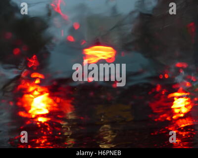 View of car brake lights through wet windshield Stock Photo