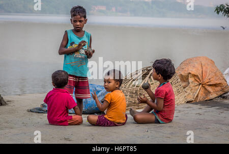 Street children play with clay from the Ganges river bank at Mallick Ghat, flower market, Kolkata, India. Stock Photo