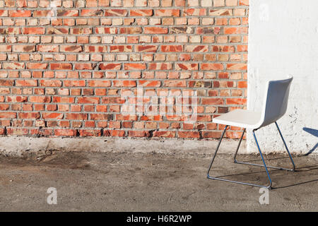 Abstract empty interior background, white office chair stands on gray concrete floor near red brick wall