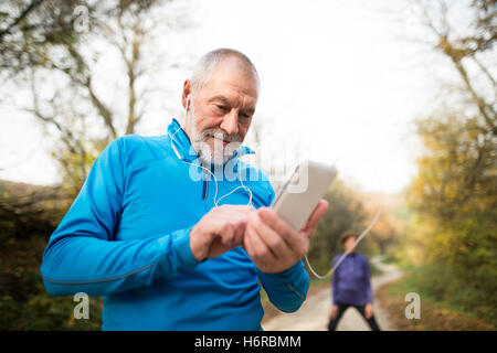 Senior runners in nature, stretching. Man with smartphone with e Stock Photo