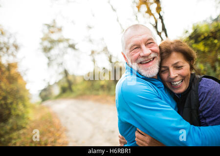 Beautiful senior couple running outside in sunny autumn forest Stock Photo