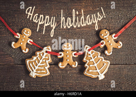 painted by gingerbread cookie card with an inscription on a ribbon on the dark background. Stock Photo