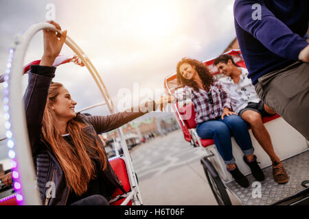 Teenage friends having fun on tricycles in the city. Young man and women riding on tricycle on road. Stock Photo