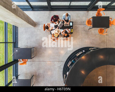Top view of college students sitting in a library with books and laptop. Young people studying together at public library. Stock Photo