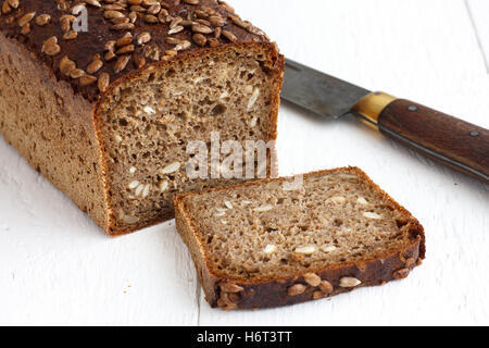 Square sunflower seed loaf sliced on rustic white surface. Stock Photo