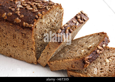 Square sunflower seed loaf sliced on rustic white surface. Stock Photo