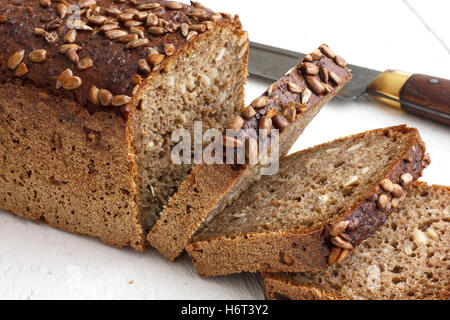 Square sunflower seed loaf sliced on rustic white surface. Stock Photo
