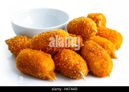 Pile of fried breaded surimi crab claws with empty dip bowl isolated on white. Stock Photo