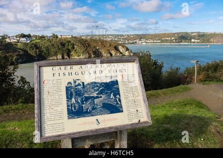 Bilingual tourist information board for historic fort with view to port in Pembrokeshire Coast National Park. Fishguard South Wales UK Stock Photo