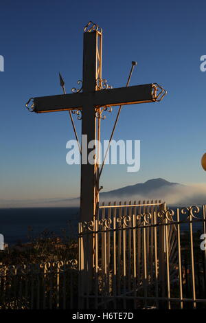 Sign of the cross Mount Vesuvius seen in the background shrouded in mist metal railings surrounding the cross protection evil. Stock Photo