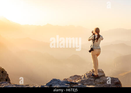 A woman is taking photos of Al Hajar Mountains in Oman at sunset Stock Photo