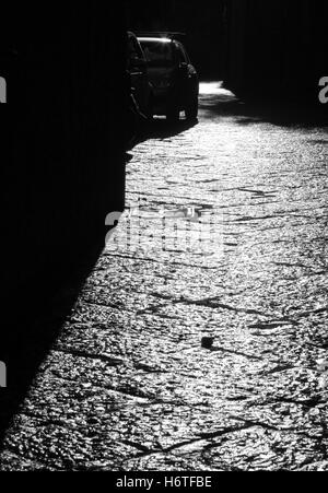 Long black shadows cast by sun early morning on road paved Italian Sorrento Roman interlocking grid stone slabs hard wearing. Stock Photo