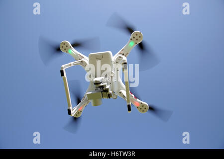 White drone quad copter with flying in the clear blue sky Stock Photo