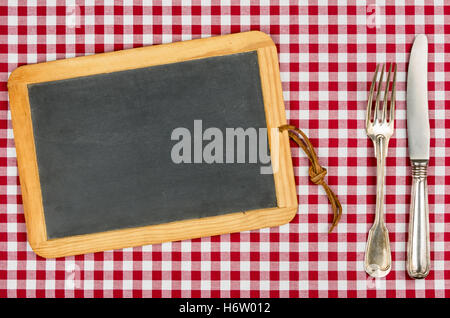 blank slate with silverware on a red checkered tablecloth Stock Photo