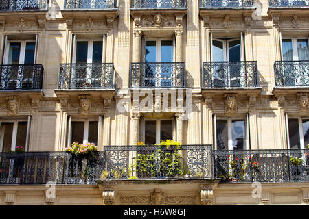 View of a traditional building in Paris showing French architectural style. Carvings and iron work balconies and some flowers cr Stock Photo