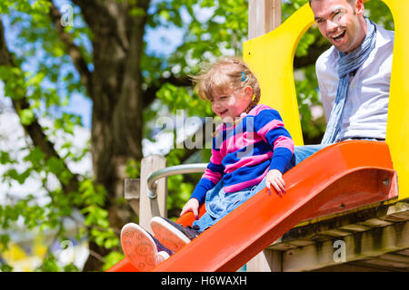 father and daughter on slide at playground
